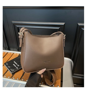 Detail of a brown textured shoulder bucket bag featuring NEW YORK lettering and gold hardware