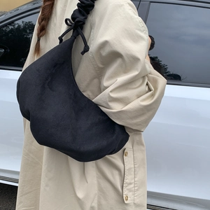 Detail of minimalist black pleated dumpling bag featuring unique drawstring knot shoulder strap