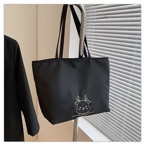 Detail of black nylon tote bag featuring gold deer embroidery and long shoulder straps