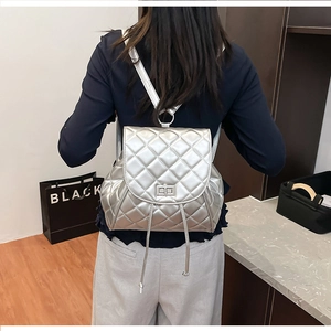 Silver quilted backpack with metallic finish featuring flap closure and sleek metal lock