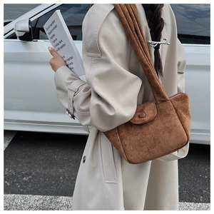 Close-up of a brown suede shoulder bag with a magnetic snap button on the flap