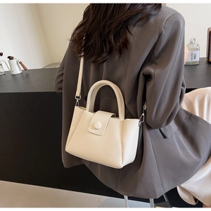 Detailed back view of a creamy white litchi pattern leather bucket bag on a model