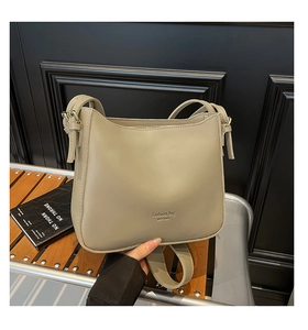Detail of khaki textured shoulder bucket bag with gold lettering and adjustable strap