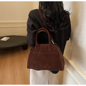 Détail du sac cabas en daim marron foncé avec poignées arrondies et bandoulière