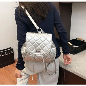 Silver quilted backpack with metallic finish and metal twist lock closure on back