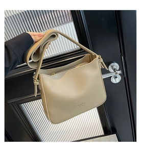 Detalle del bolso tipo cubo de cuero sintético beige con estampado y correa ajustable
