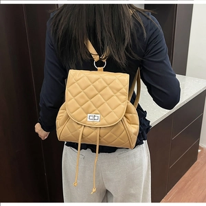 Detail of yellow quilted leather backpack with silver twist lock and drawstring accents