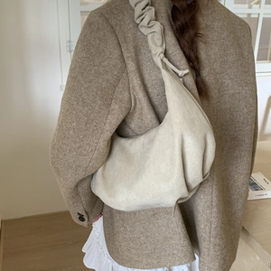 Chic beige pleated hobo bag worn over the shoulder featuring soft texture and minimalist style