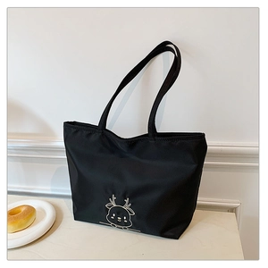 Detail of black nylon tote bag with golden reindeer embroidery in a clean lifestyle setting