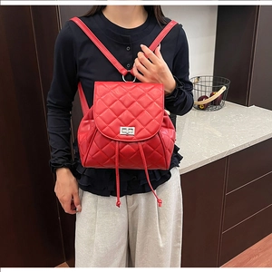 Detail of red quilted backpack showing the classic metal twist lock and drawstring closure