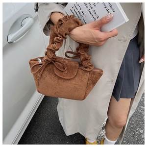 Detail view of the brown suede handbag with pleated cloud handle and bow decoration