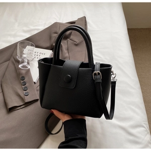 Détail d'un sac seau en cuir grainé noir avec poignée cylindrique et bouton pression