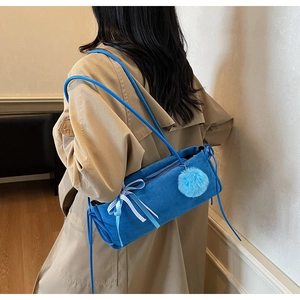 Detailansicht der kobaltblauen Wildledertasche mit Plüsch-Anhänger und Karo-Schleife