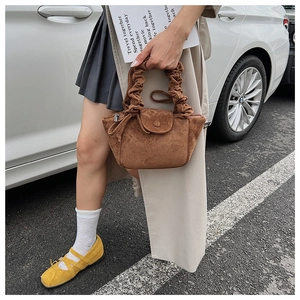 Detail of vintage brown suede shoulder bag with pleated handle and matte finish texture