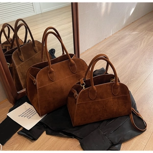 Détail macro de sacs cabas en daim marron foncé en deux tailles avec courbes vintage