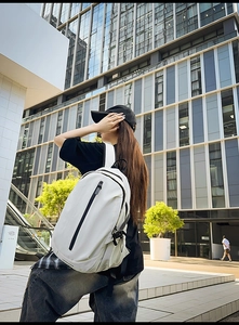 Close-up of white nylon travel backpack with adjustable side buckles and vertical zipper