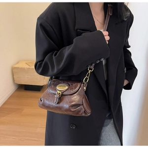 Detail of dark brown vintage faux leather crossbody bag with metallic buckle and gold plate