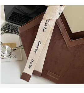 Detail of dark brown suede tote bag with V-cut opening and wide branded strap