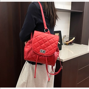 Close-up of red quilted backpack showing the silver metal twist lock and drawstring closure