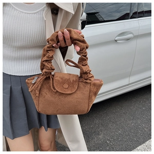 Close-up of the brown suede handbag featuring a unique pleated cloud-style top handle