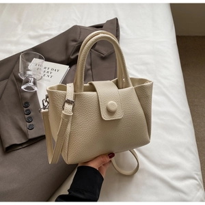 Détail du sac seau en cuir grainé blanc crème avec ferrures argentées et bandoulière réglable