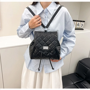 Detail of black quilted leather backpack with silver rotating clasp and drawstring closure