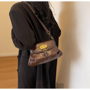 Detail of dark brown vintage crossbody bag with gold hardware on a shoulder strap