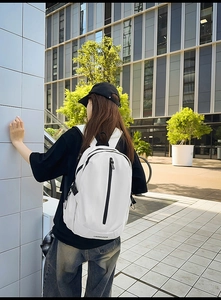 Close-up of a white travel backpack featuring a black vertical zipper and side buckle detail