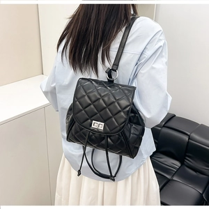 Detailed view of the black quilted backpack with silver lock on the model back