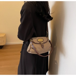 Detail of vintage houndstooth crossbody bag with brown leather trim and golden buckle