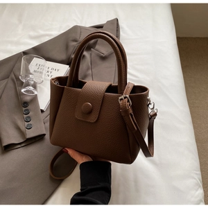 Détail du sac à main en cuir marron avec double poignée et bandoulière amovible