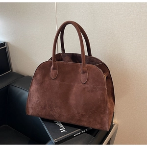 Détail d'un sac cabas en daim marron foncé avec deux poignées rondes et coutures apparentes