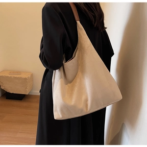 Side view of model wearing a large beige suede tote bag with brown leather straps