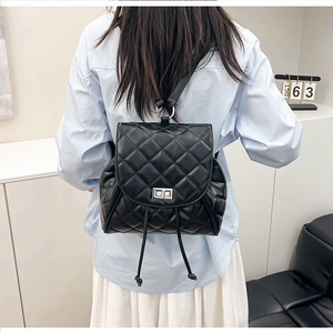 Quilted black leather backpack with silver twist lock shown on a model in a minimalist setting
