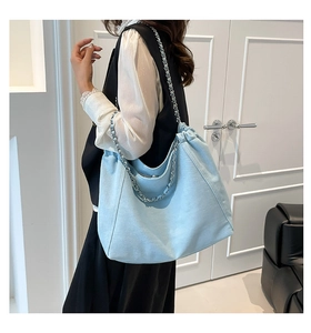 Detail der hellblauen Denim-Tote-Bag mit verflochtener Silberkette und Stoffriemen