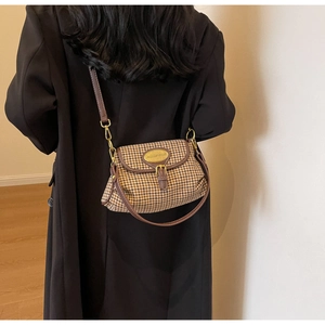 Close-up of houndstooth crossbody bag featuring oval gold hardware and leather details