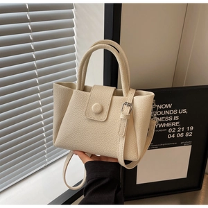Détail du sac seau en cuir crème avec grain litchi et bandoulière réglable pratique