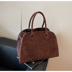 Détail du sac cabas en daim marron foncé avec poignées circulaires et structure en arche