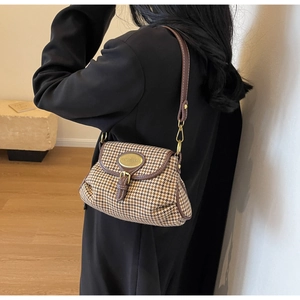 Brown houndstooth crossbody bag detail showing leather trim and gold buckle on a model