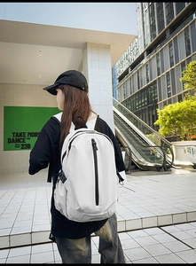 Side view of white travel backpack with contrast black zippers on a modern city street