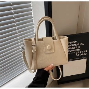 Détail du sac à main en cuir grainé beige montrant la texture et les boucles métalliques