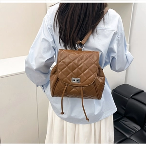 Close-up of brown quilted faux leather backpack featuring silver twist lock and drawstring