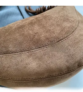 Detail of brown suede leather bag featuring high-quality stitching and soft texture
