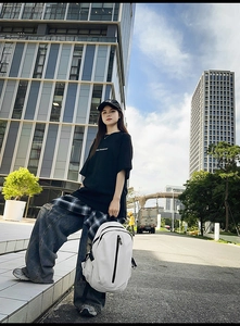 Detailed street view of a white minimalist large capacity travel backpack worn by a model