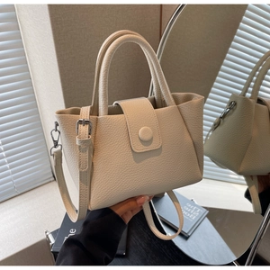 Détail du sac seau crème montrant la texture cuir grainé et la poignée arrondie