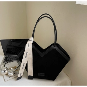 Detail of matte black tote bag with V-shaped opening and decorative logo ribbon