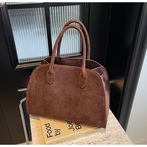 Détail de la texture en daim marron foncé et de la poignée ronde du sac à main