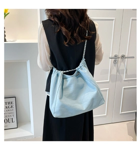 Detail of light blue denim tote bag with silver chain strap and drawstring closure