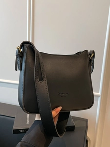 Minimalist black matte leather bucket bag with wide shoulder strap and modern lettering