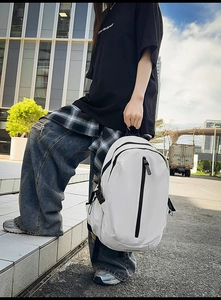 Detail of white water-resistant backpack showing reinforced side straps and black zippers